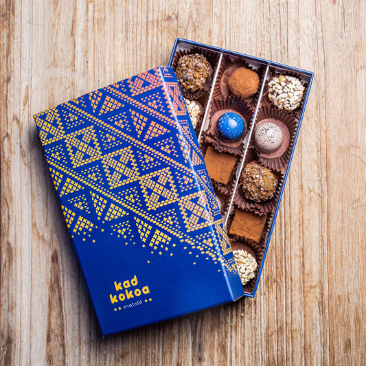 Blue and gold chocolate box with assorted chocolates on a wooden surface