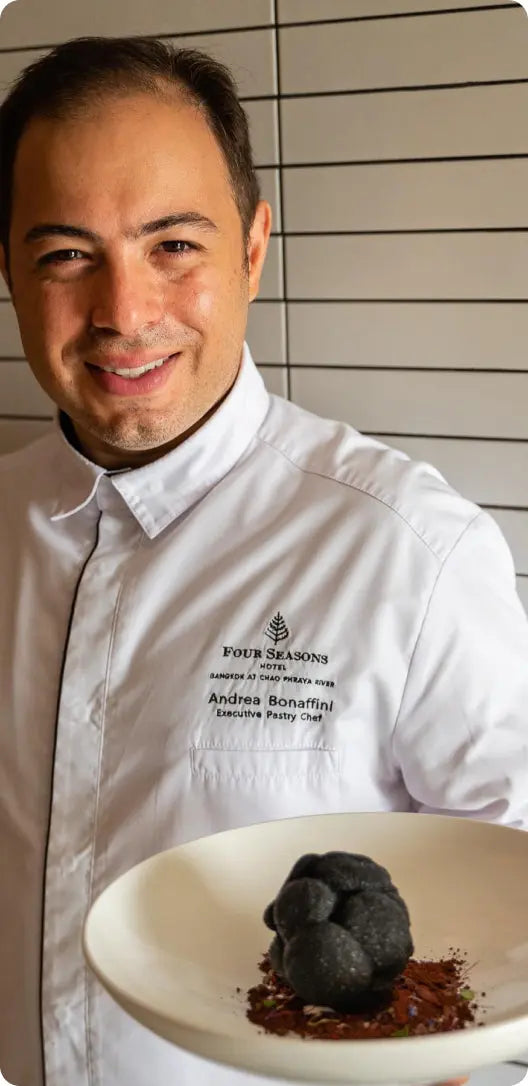 Andrea Bonaffini, Executive Pastry Chef at Four Seasons Bangkok, holding a chocolate dessert plate