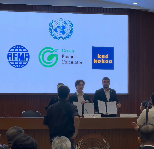Group of people at a conference with a screen displaying logos of AFMA, Green Finance Calculator, and kad kokoa.